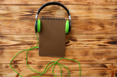 Modern headphones and notebook on wooden backgroundの写真素材