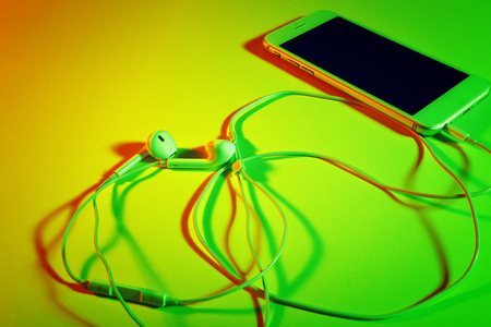 Mobile phone with earphones on bright color backgroundの写真素材