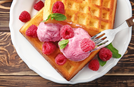 Delicious waffles with raspberries and ice cream on plateの写真素材