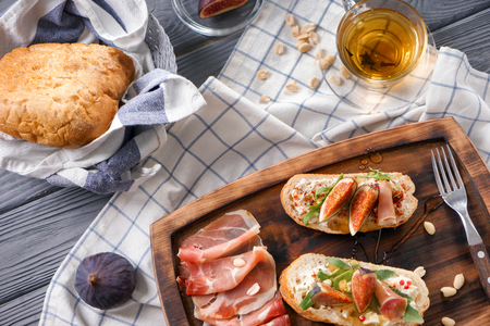 Tasty sandwiches with ripe fig and prosciutto on wooden boardの写真素材
