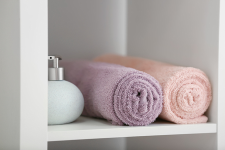 Clean soft towels and soap dispenser on shelfの写真素材
