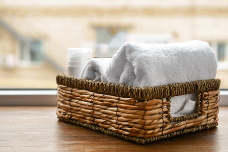 Wicker basket with clean soft towels on windowsillの写真素材