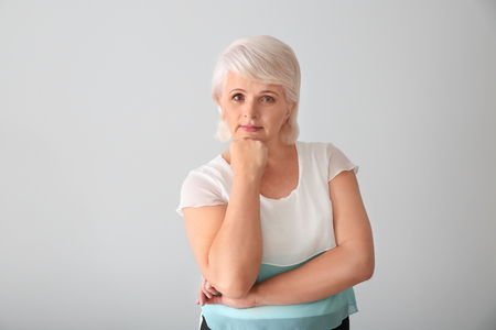 Portrait of thoughtful mature woman on light backgroundの写真素材