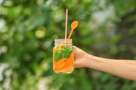 Woman holding mason jar of fresh summer cocktail outdoorsの写真素材