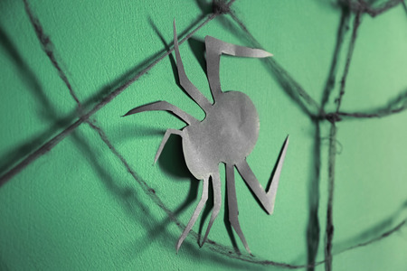Paper spider with web as decor for Halloween party on color backgroundの写真素材