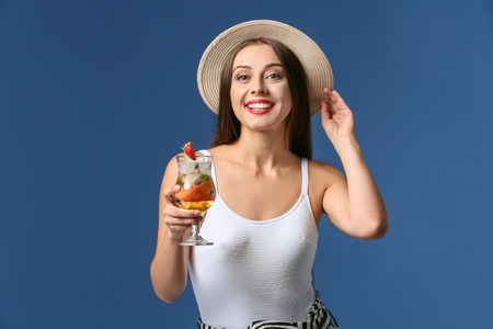 Beautiful woman with tasty summer cocktail on color background