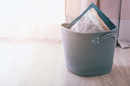 Laundry basket with folded clothes on floor near windowの写真素材