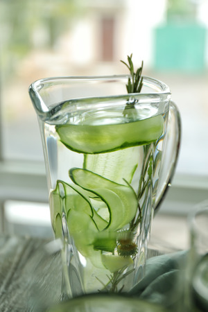 Jug of fresh cucumber water on tableの写真素材