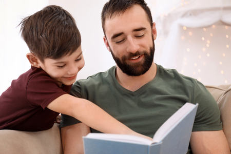 Man reading book to his child at homeの写真素材