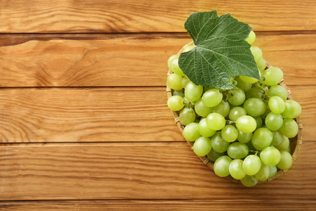 Plate with ripe sweet grapes on wooden background, top viewの写真素材