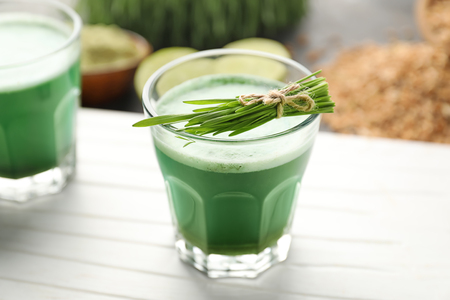 Glass of wheat grass juice on white boardの写真素材