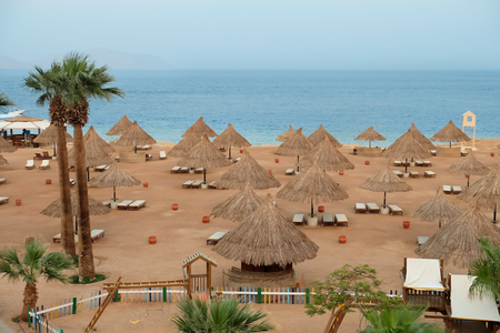 View of beach with comfortable sun loungers at resortの写真素材