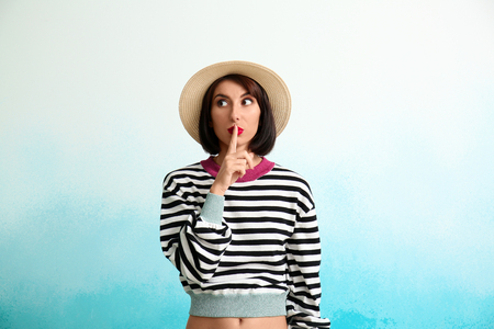 Portrait of beautiful woman showing Silence gesture on color backgroundの写真素材