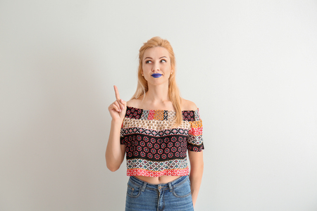 Portrait of beautiful woman with unusual lipstick and raised index finger on white backgroundの写真素材
