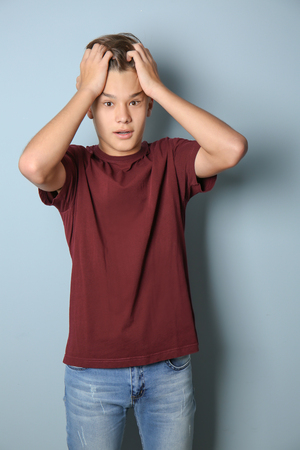 Stressed teenage boy on color backgroundの写真素材