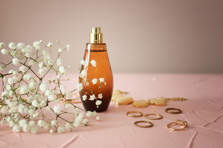 Bottle of perfume with flowers and accessories on color table
