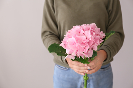 Woman holding beautiful pink flowers on light backgroundの写真素材