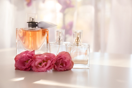 Transparent bottles of perfume with beautiful flowers on white tableの写真素材