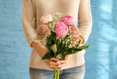 Woman holding beautiful pink flowers on color backgroundの写真素材