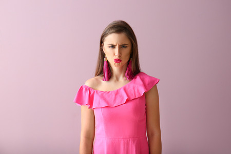 Beautiful offended young woman on color background