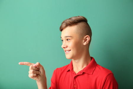 Teenage boy pointing at something on color backgroundの写真素材
