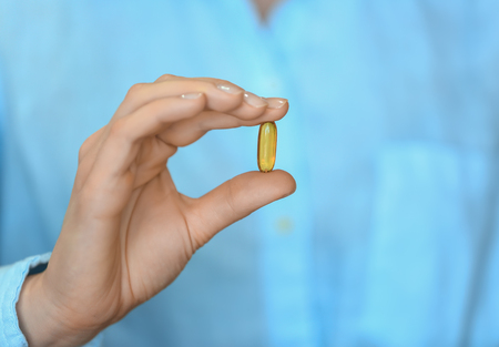 Woman holding pill, closeupの写真素材