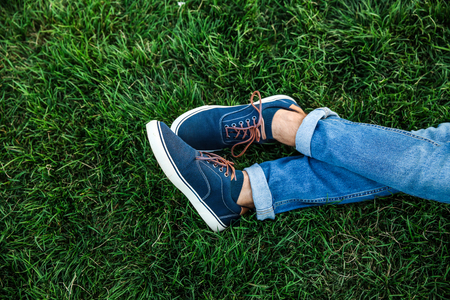 Legs of young man resting on green grass in parkの写真素材