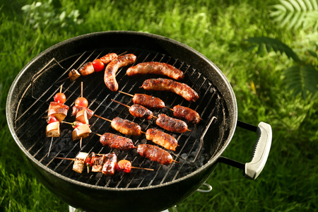 Cooking of tasty sausages and vegetables on barbecue grill outdoorsの写真素材