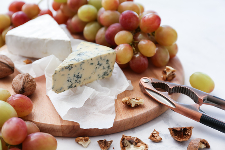 Ripe juicy grapes with cheese and walnut on wooden boardの写真素材