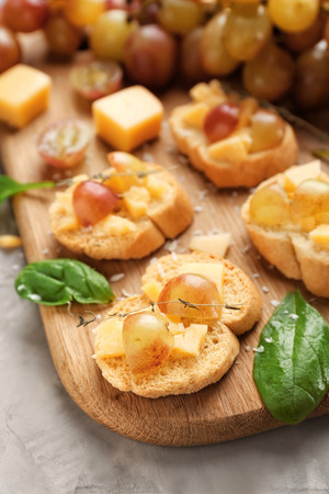 Tasty sandwiches with cheese and grape on wooden boardの写真素材