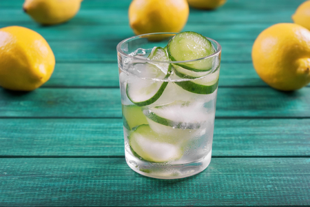 Glass of fresh cucumber water on color wooden tableの写真素材