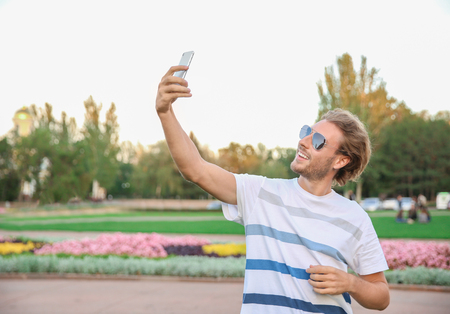 Handsome young man taking selfie in parkの写真素材
