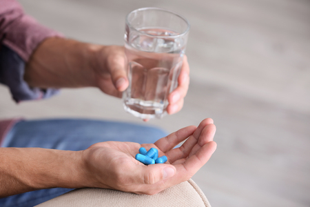 Man holding pills and glass of water, closeupの写真素材