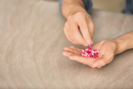 Man holding capsules on table, closeup