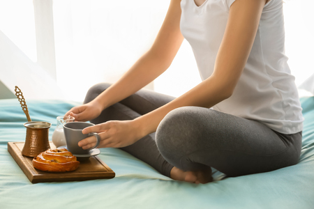 Young woman having delicious breakfast on bedの写真素材