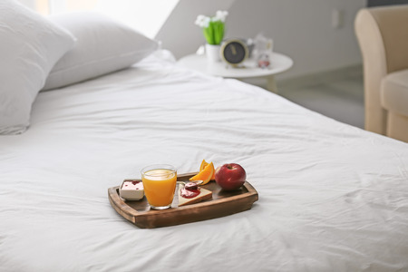 Wooden tray with delicious breakfast on bedの写真素材