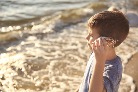 Cute little boy with sea shell on beachの写真素材