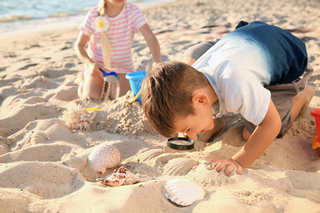 Cute little children playing with sand on sea beachの写真素材