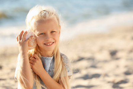 Cute little girl with sea shell on beachの写真素材