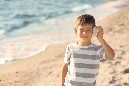 Cute little boy with shell on sea beachの写真素材