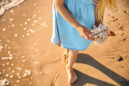 Cute little girl with coral on sea beachの写真素材