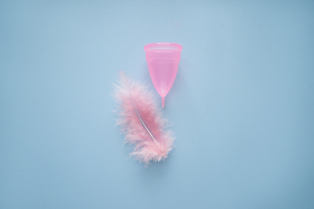 Menstrual cup with feather on color backgroundの写真素材