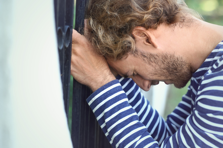 Stressed young man near fence outdoorsの写真素材