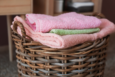 Wicker basket with folded clean towels on floorの写真素材