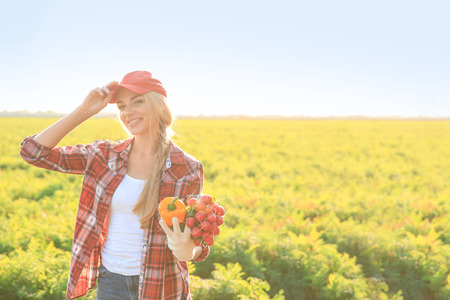 Female farmer with gathered vegetables in fieldの写真素材