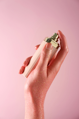 Woman holding perfume bottle on color backgroundの写真素材