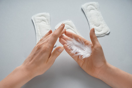 Woman with feather and menstrual pads on grey backgroundの写真素材