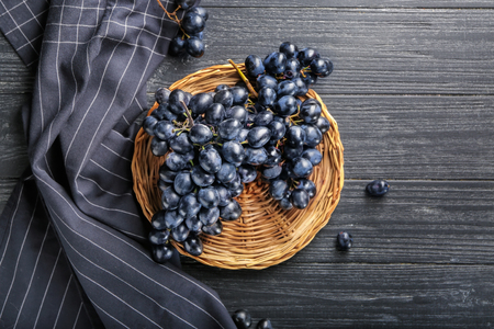 Wicker plate with ripe sweet grapes on wooden table, top viewの写真素材