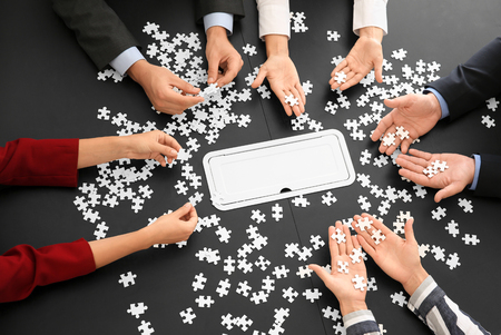 Business team assembling puzzle on dark tableの写真素材