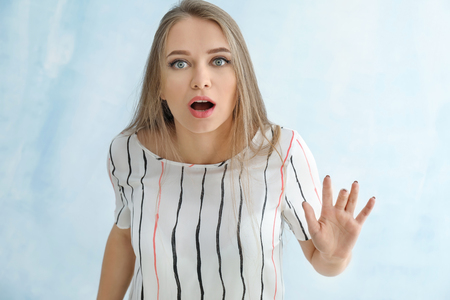 Portrait of shocked young woman on color backgroundの写真素材